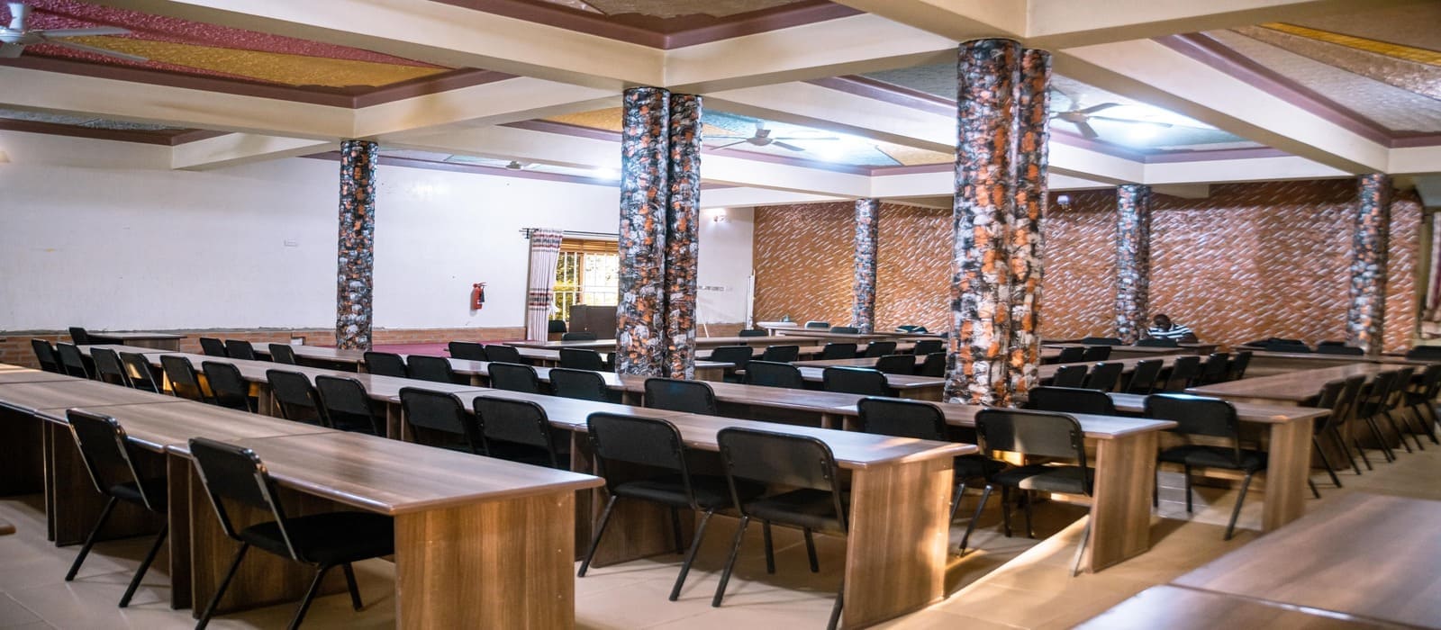 Spacious conference hall at Heritage Hotels Arua featuring decorative columns and desks for meetings or events.
